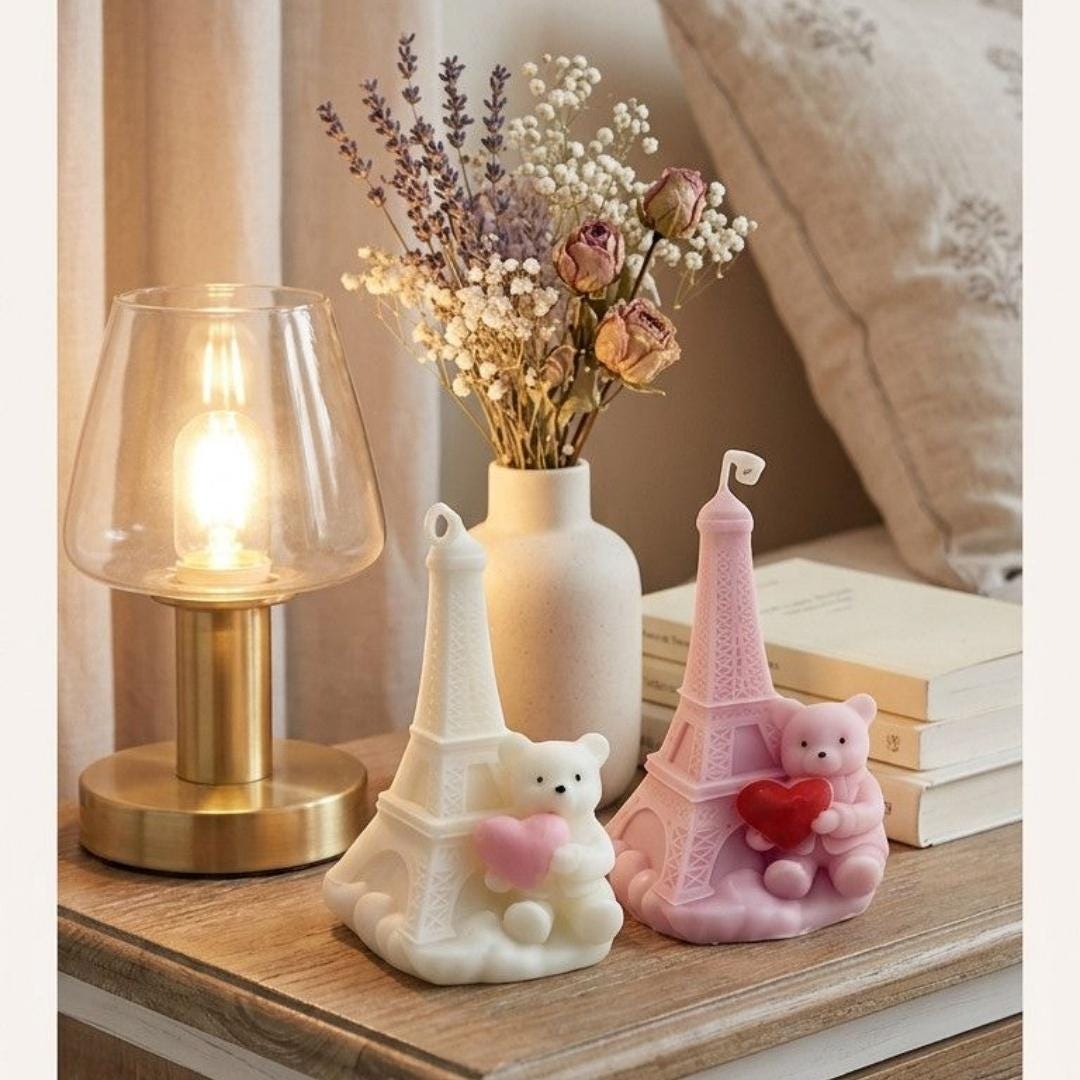 Decorative table scene with a lamp, vase of flowers, and two teddy bear figurines on a wooden surface.