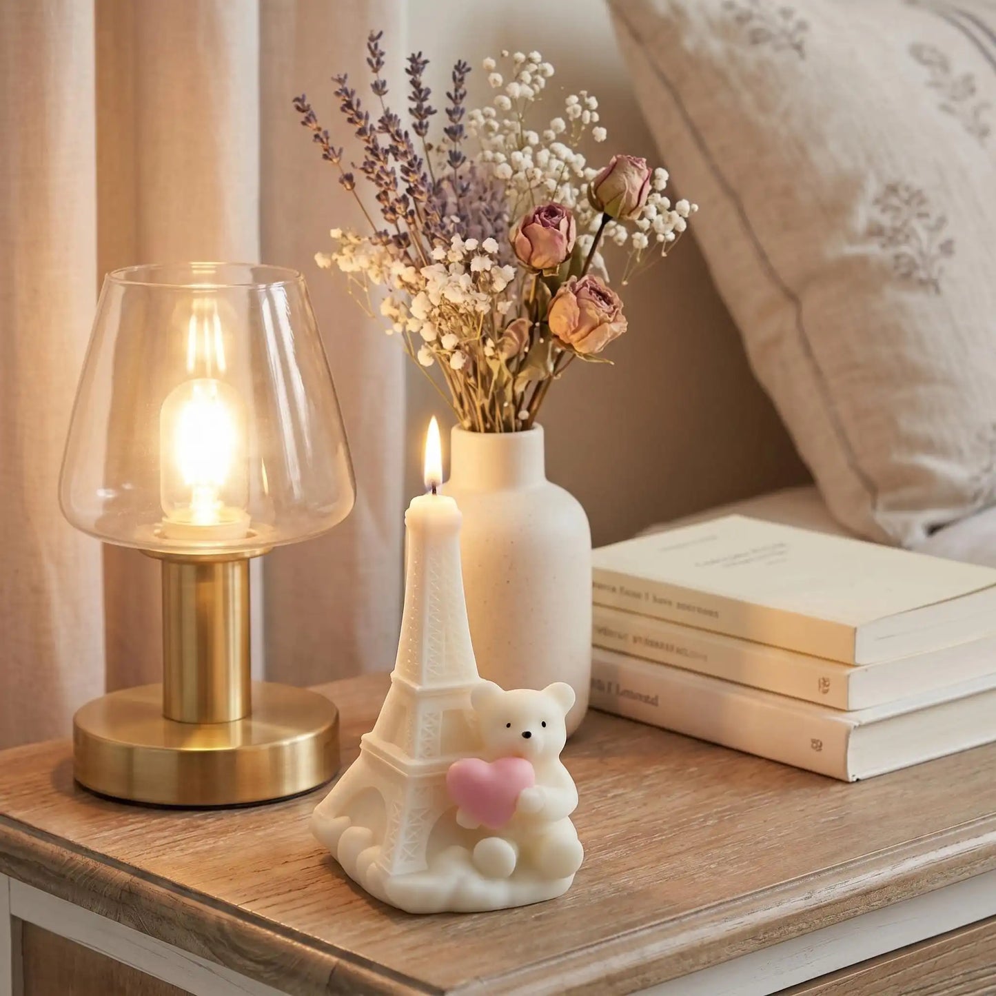 Decorative items on a wooden surface including a lamp, vase with flowers, and small statue of Eiffel Tower with a bear.