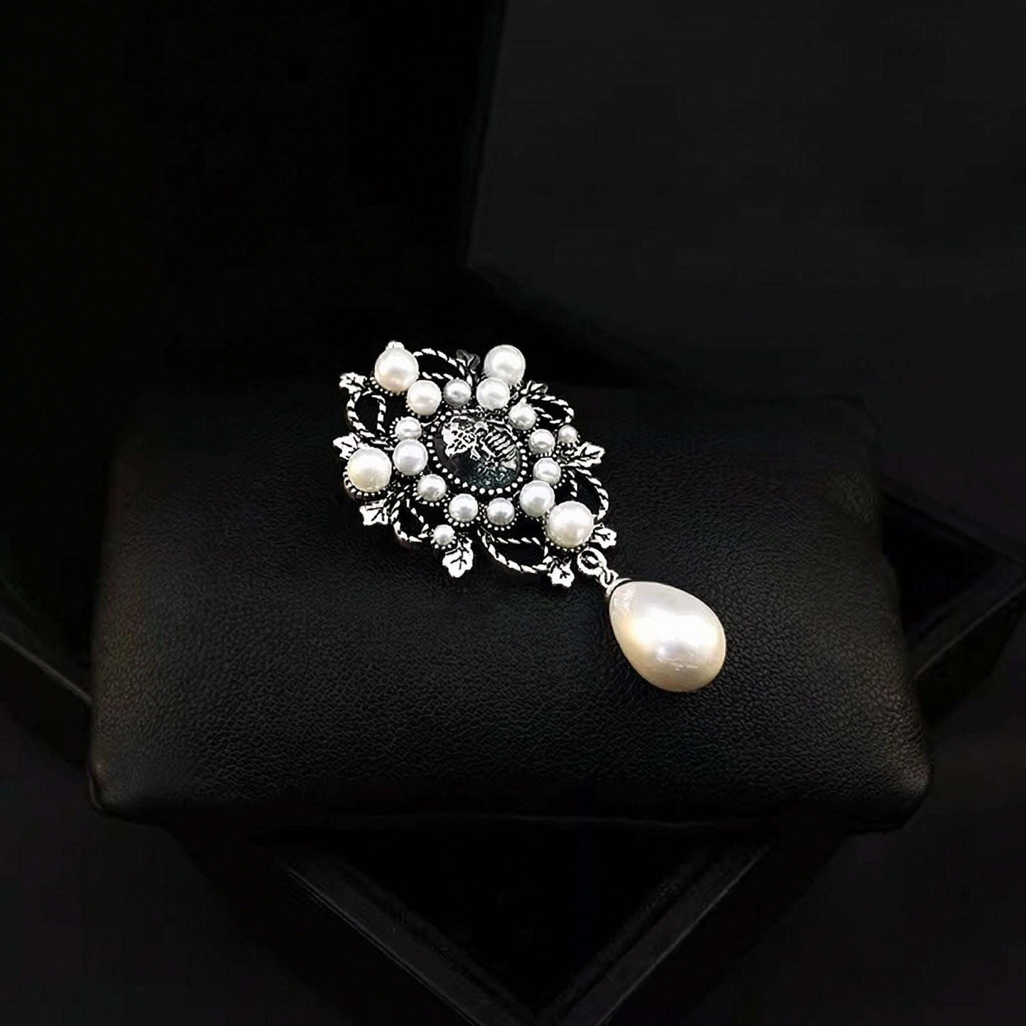 Pearl brooch on a black cushion with a dark background