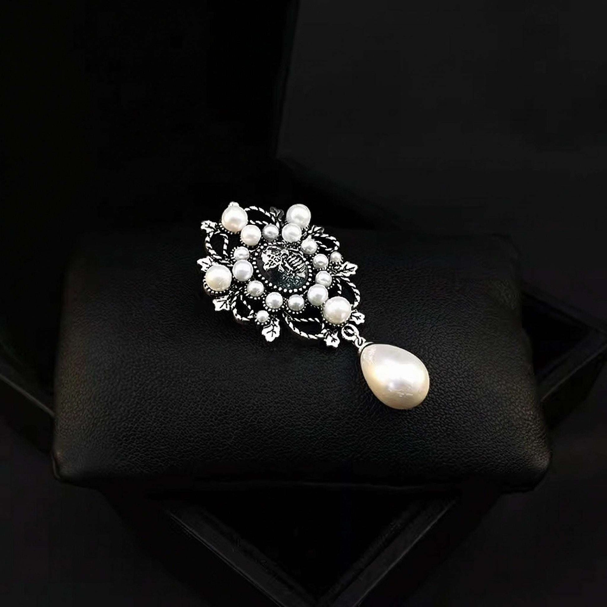 Pearl brooch on a black cushion with a dark background