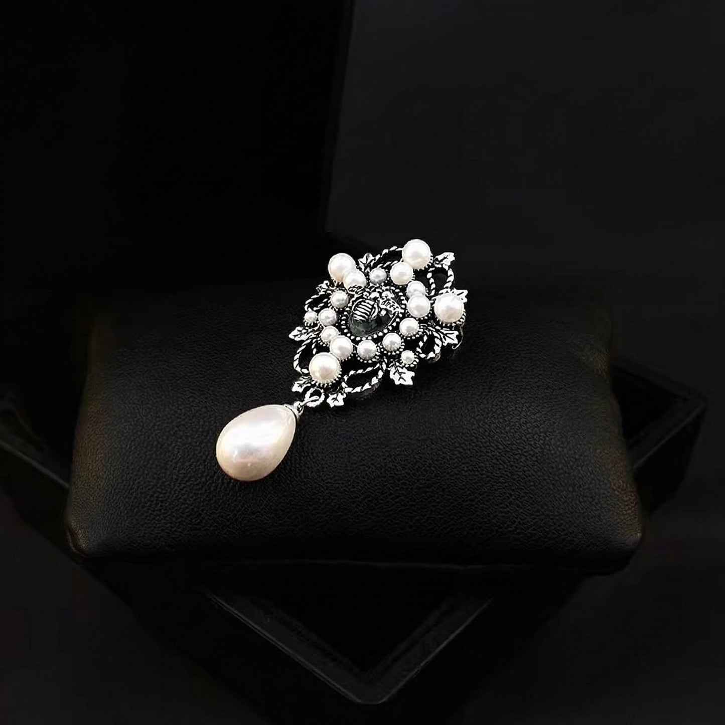 Pearl brooch on a black cushion with a dark background