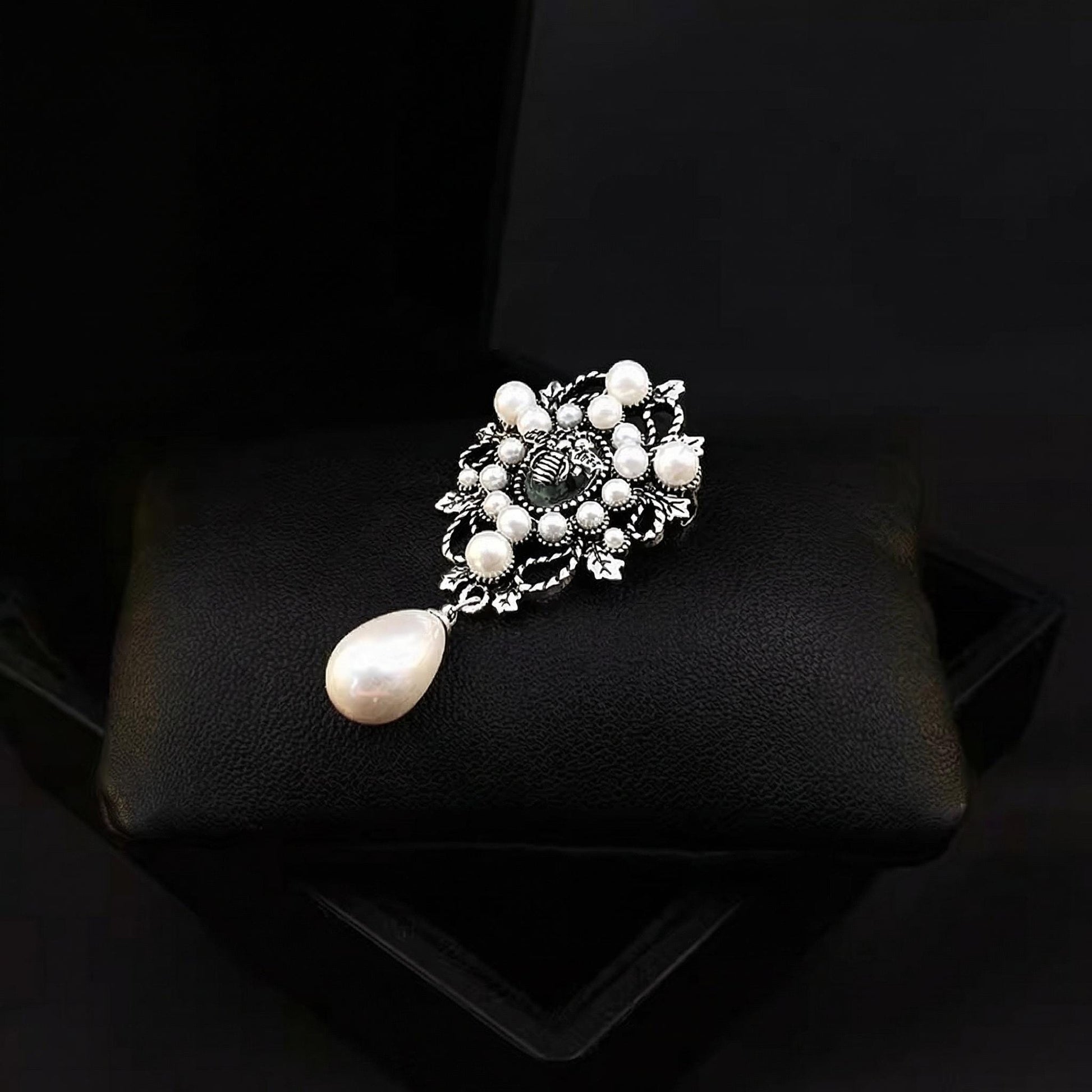 Pearl brooch on a black cushion with a dark background