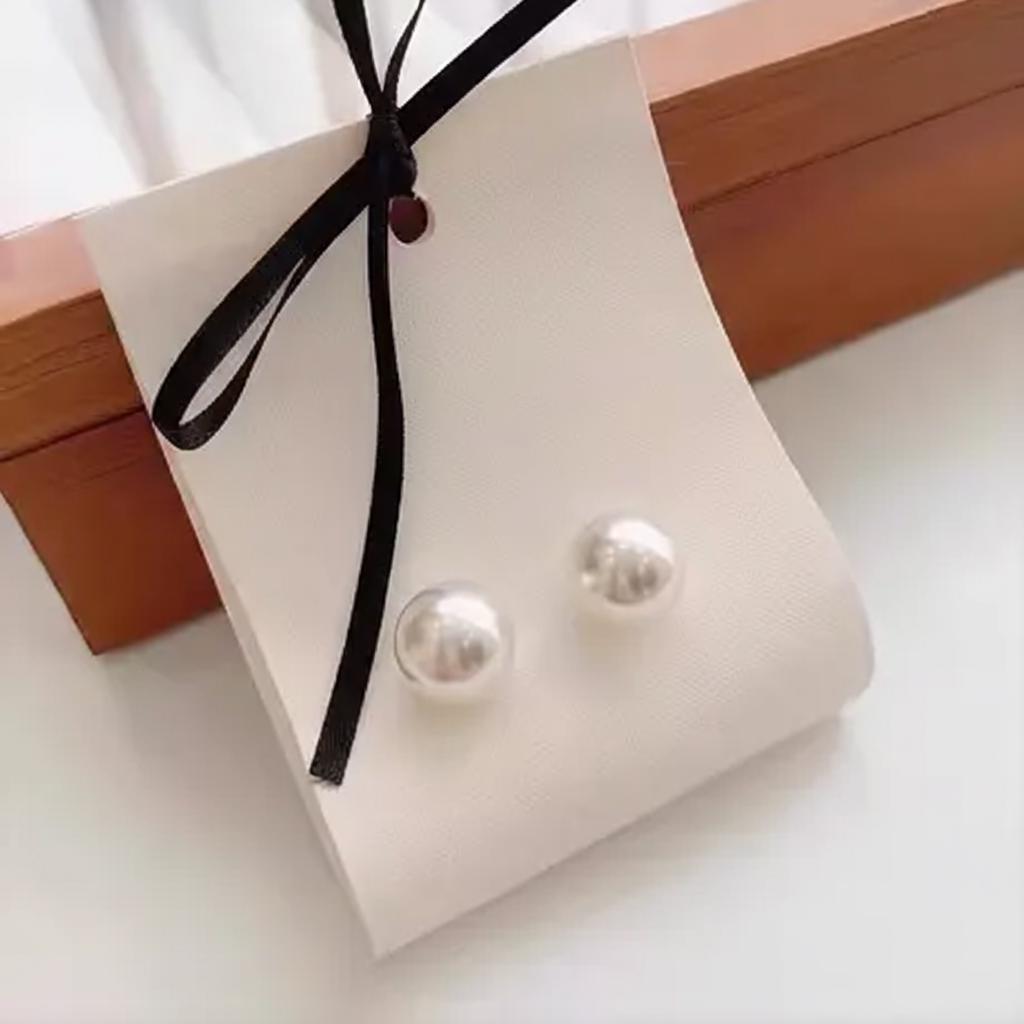 Pearl earrings on a white card with a black ribbon