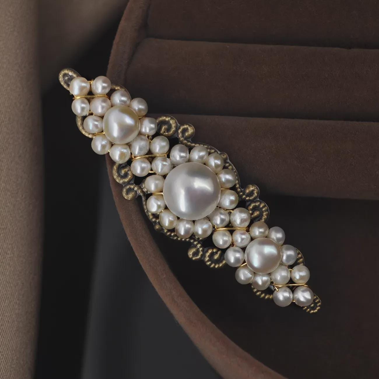 Pearl brooch on a brown fabric background
