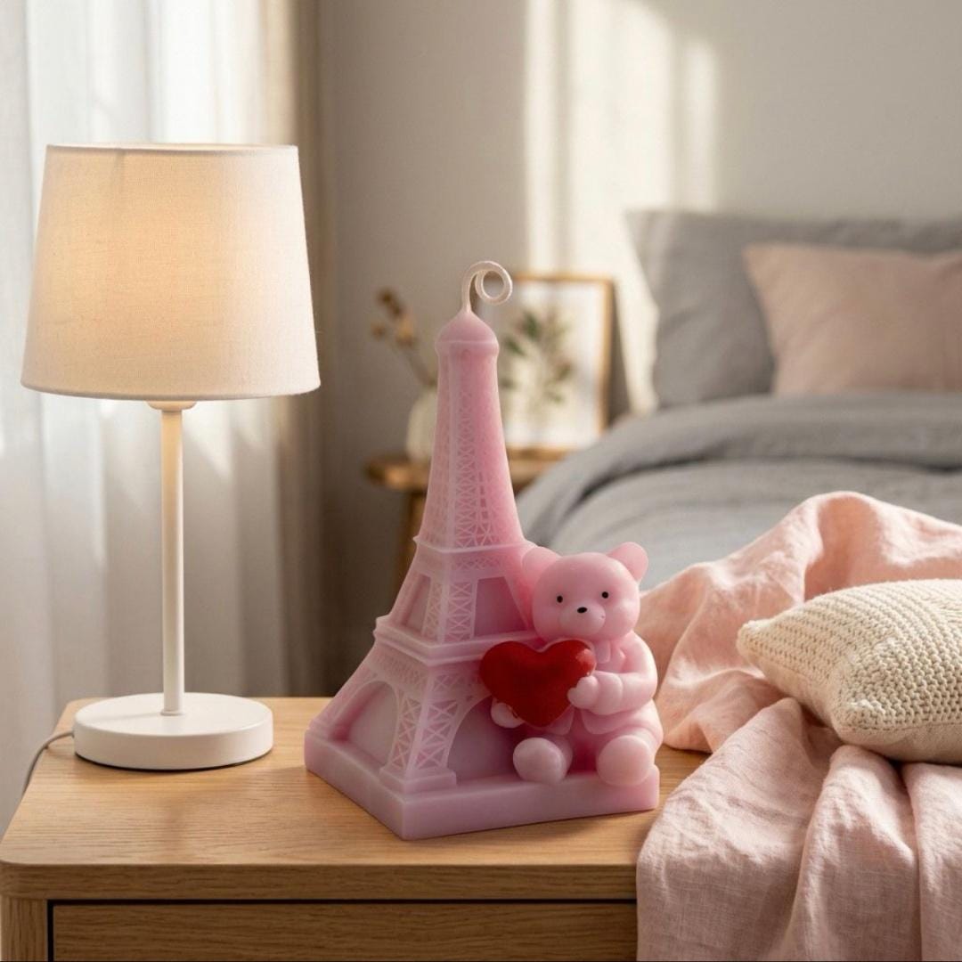 Pink Eiffel Tower decoration with a teddy bear holding a heart on a bedside table.
