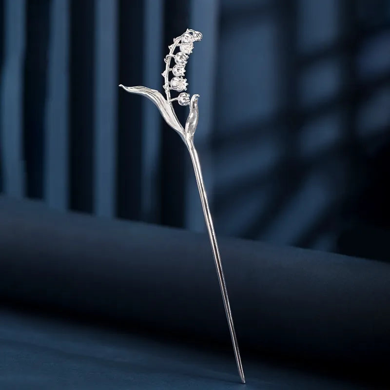 Silver hairpin with floral design on a dark blue background