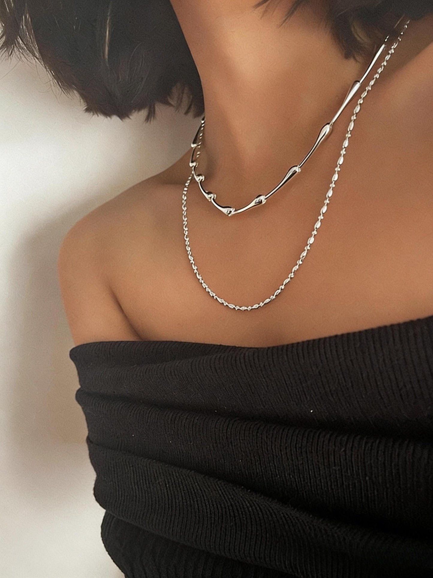 Silver chain necklace worn by a person with a blurred background