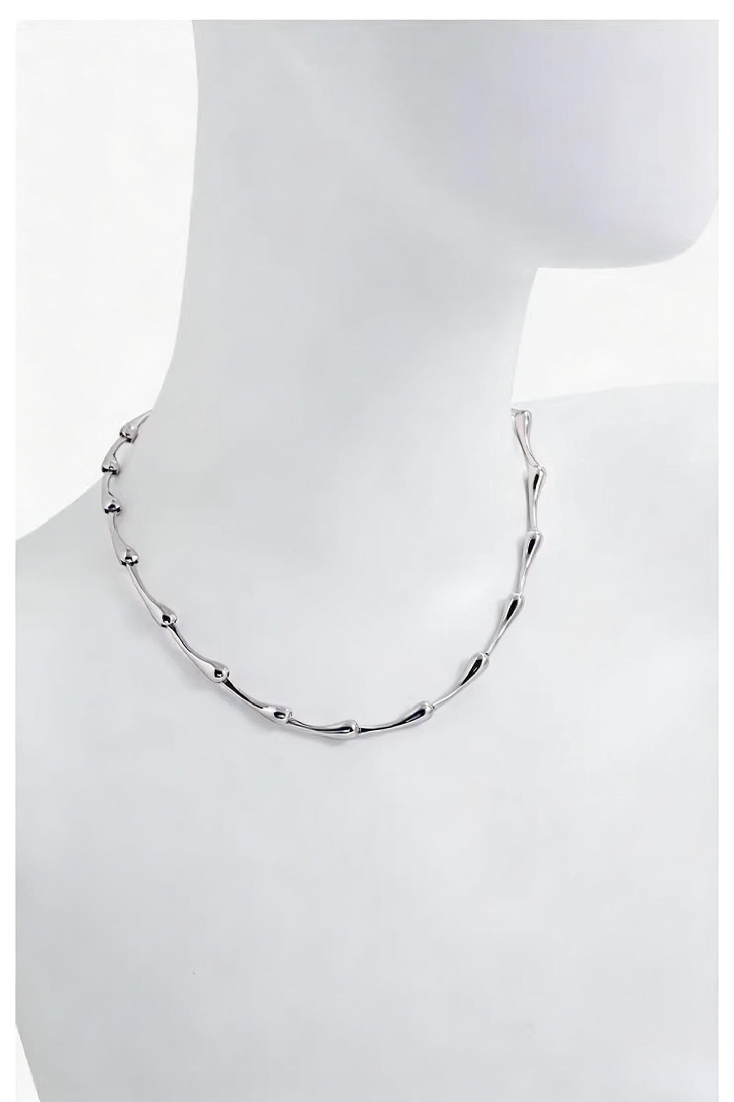 Silver necklace on a mannequin with a white background