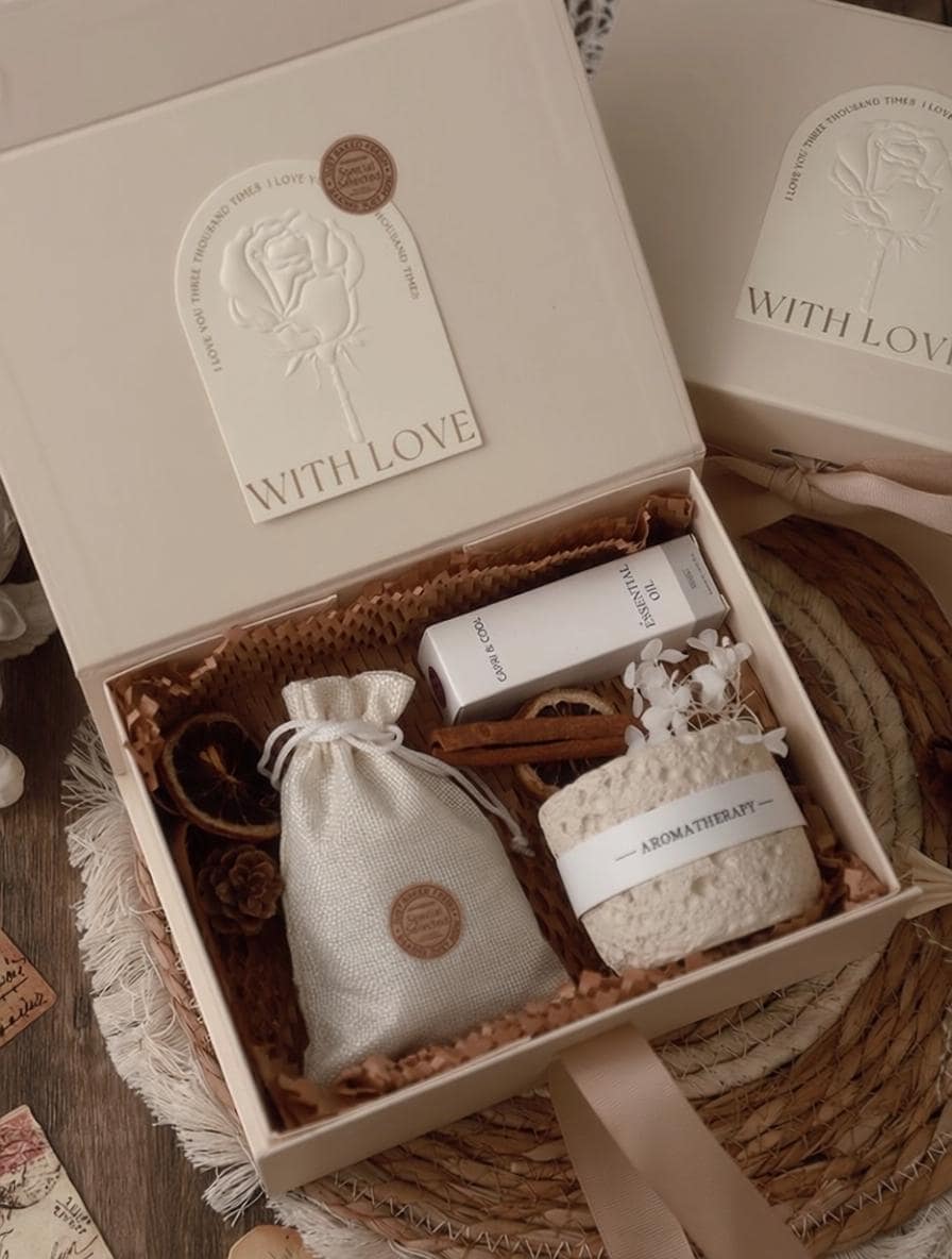 Gift box with bath products and a candle on a textured surface