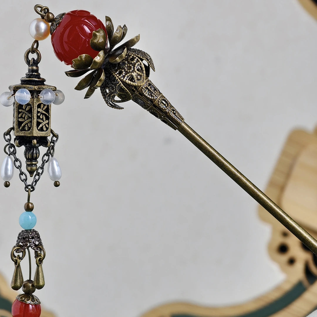 Decorative hairpin with red and gold elements on a plain background