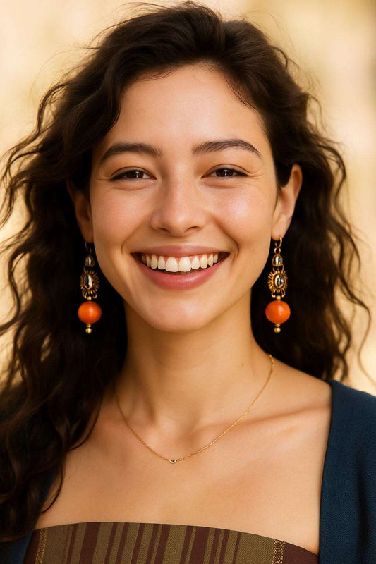 Woman wearing earrings with orange beads against a beige background