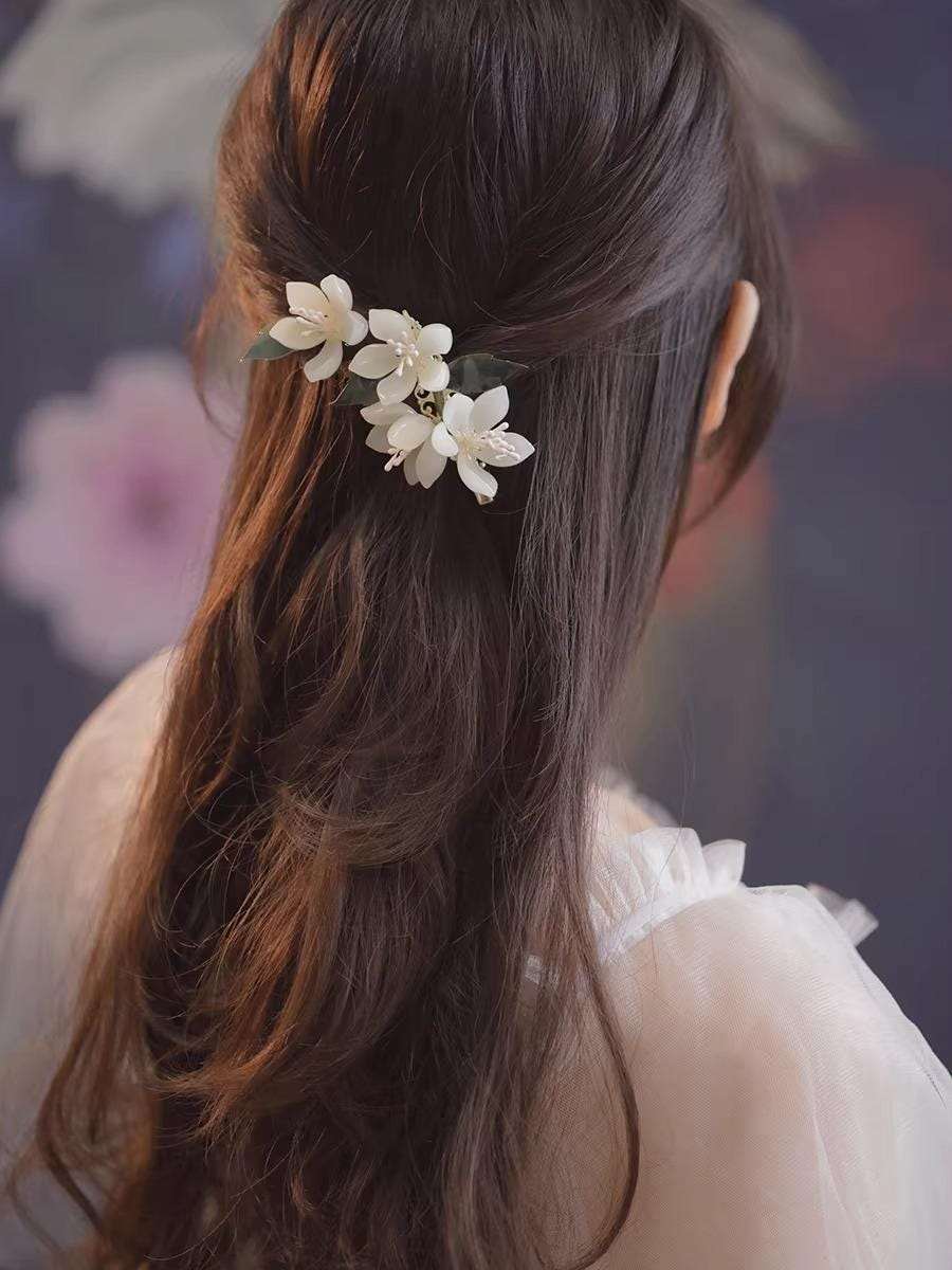 Woman with long hair wearing a floral hair accessory against a floral background