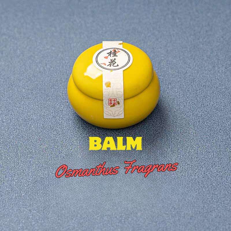 Yellow balm with a label on a blue background, labeled 'Balm Osmanthus Fragrans'.