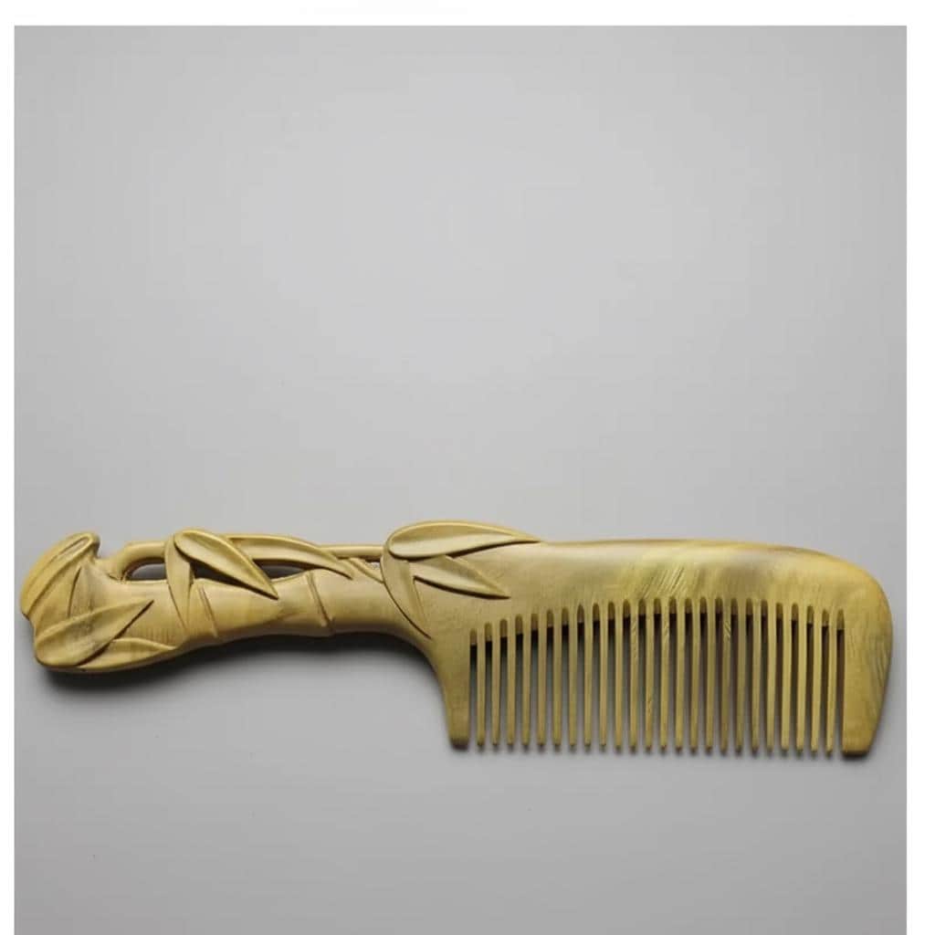 Bronze comb with decorative handle on a gray background