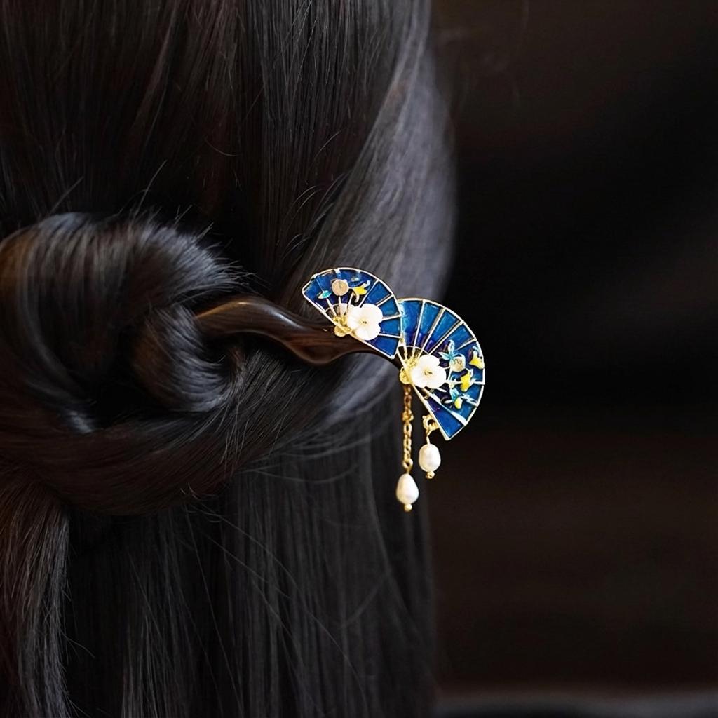 Decorative hair clip with blue fan design and pearl-like elements on a dark background