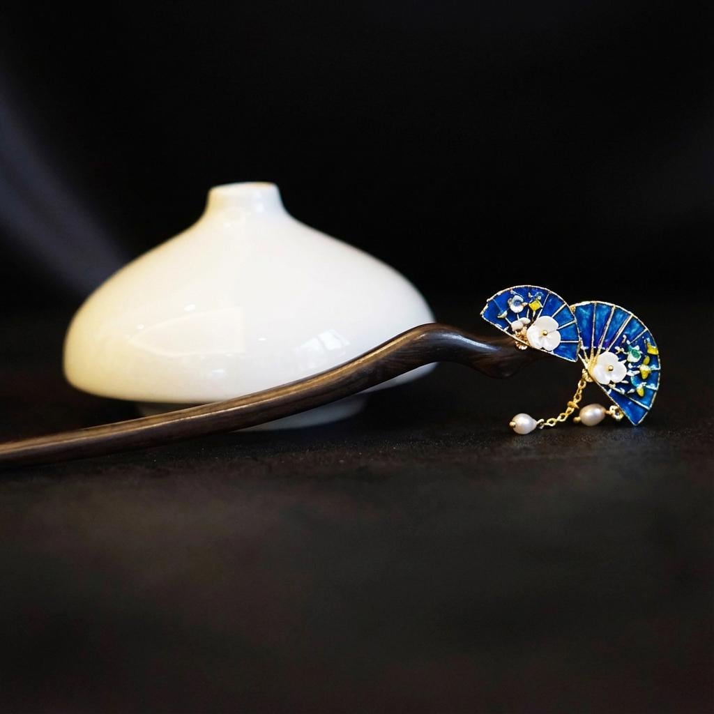 Decorative hairpin with blue and gold design on a dark background