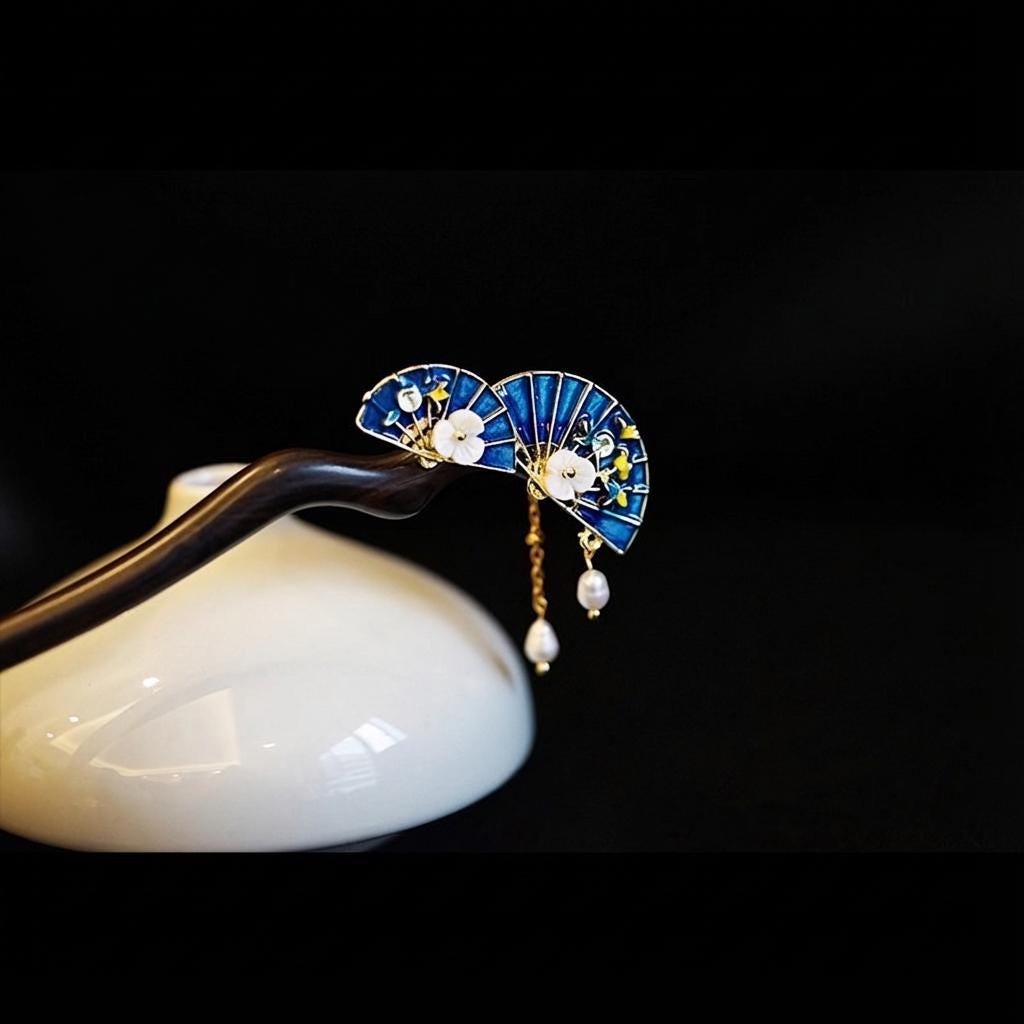 Decorative hairpin with blue fan design and pearl details on a black background
