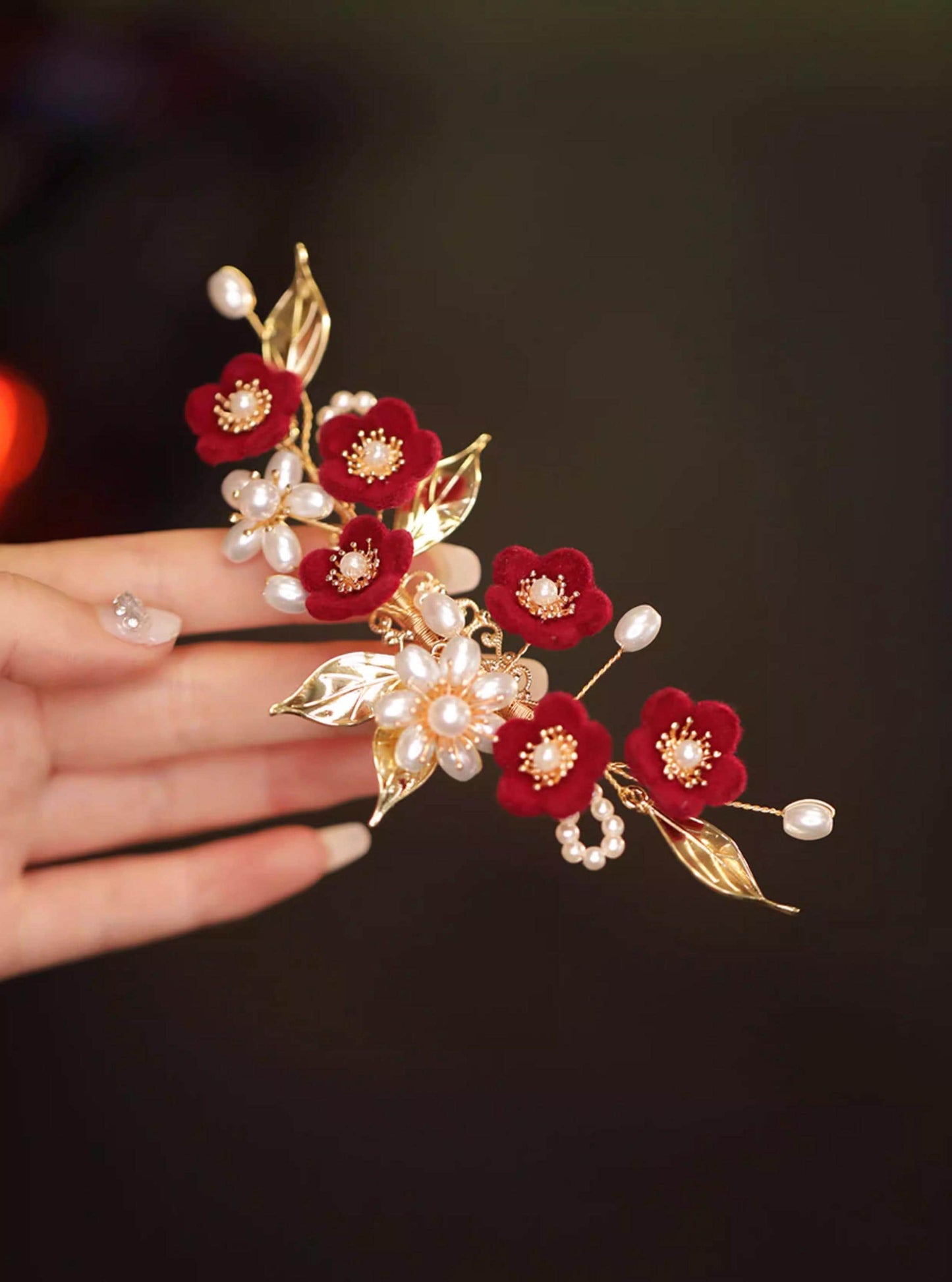 Red Poppy Ronghua Velvet Flower Hair Clip held by a hand against a dark background