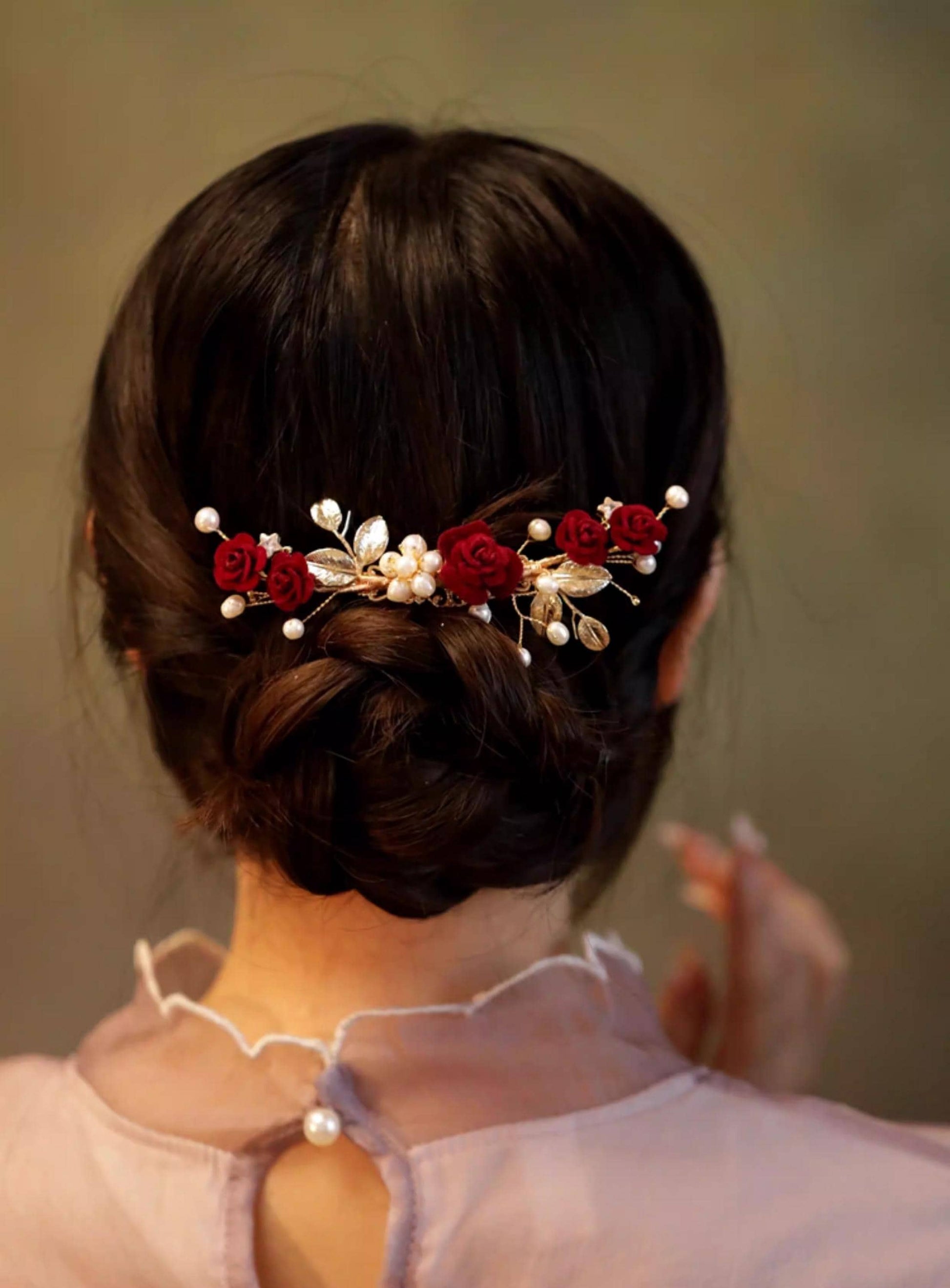 Person with braided hair wearing a decorative hairpiece with red flowers and pearls.