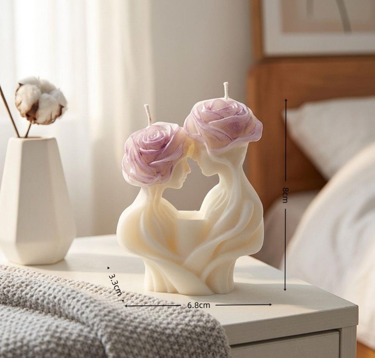 Decorative candle sculpture of two faces with floral designs on a table.