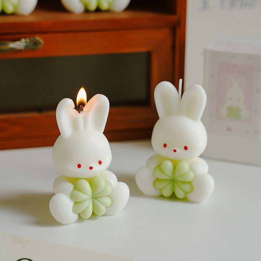 Two rabbit-shaped candles on a table with a blurred background