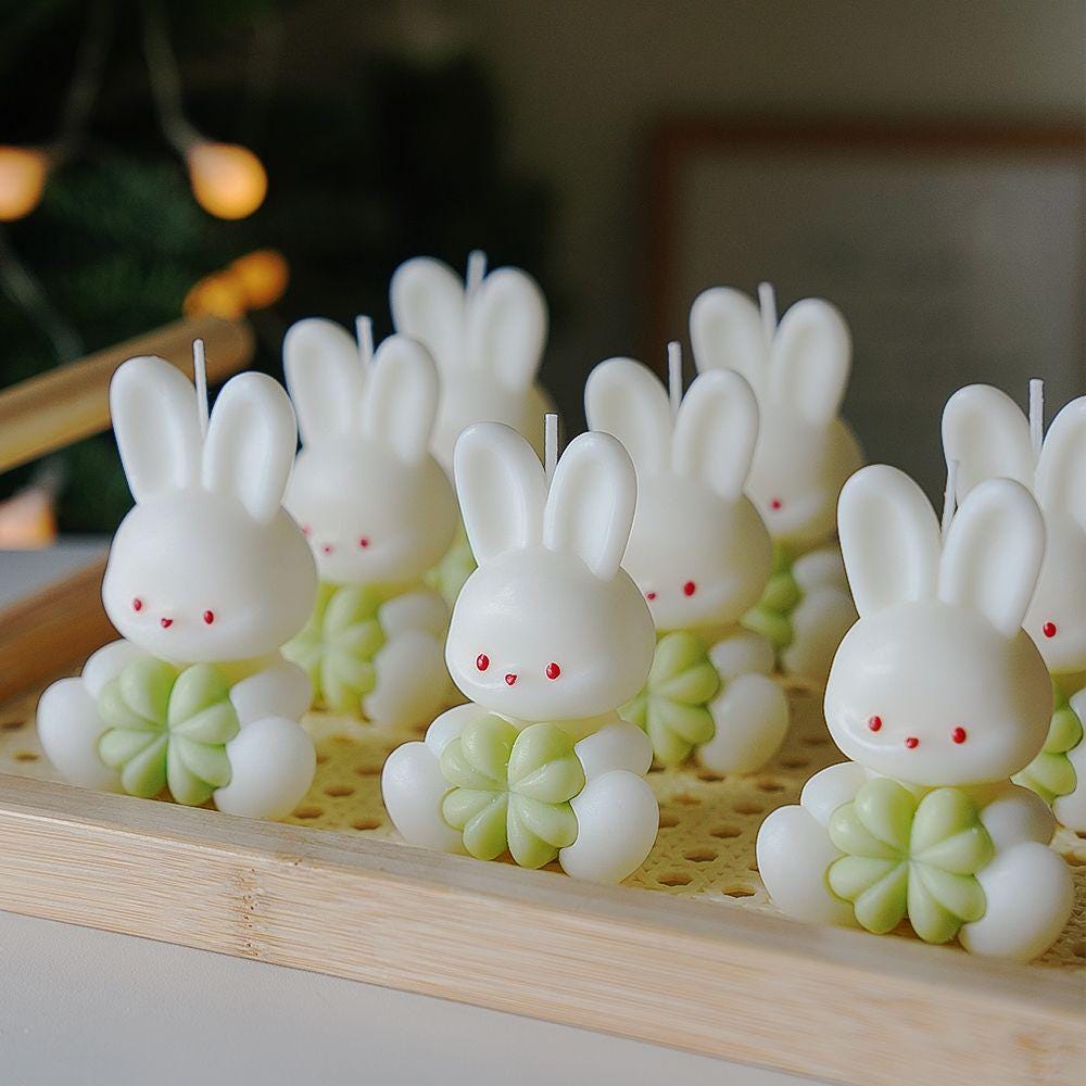Bunny-shaped candles on a wooden tray with a blurred background