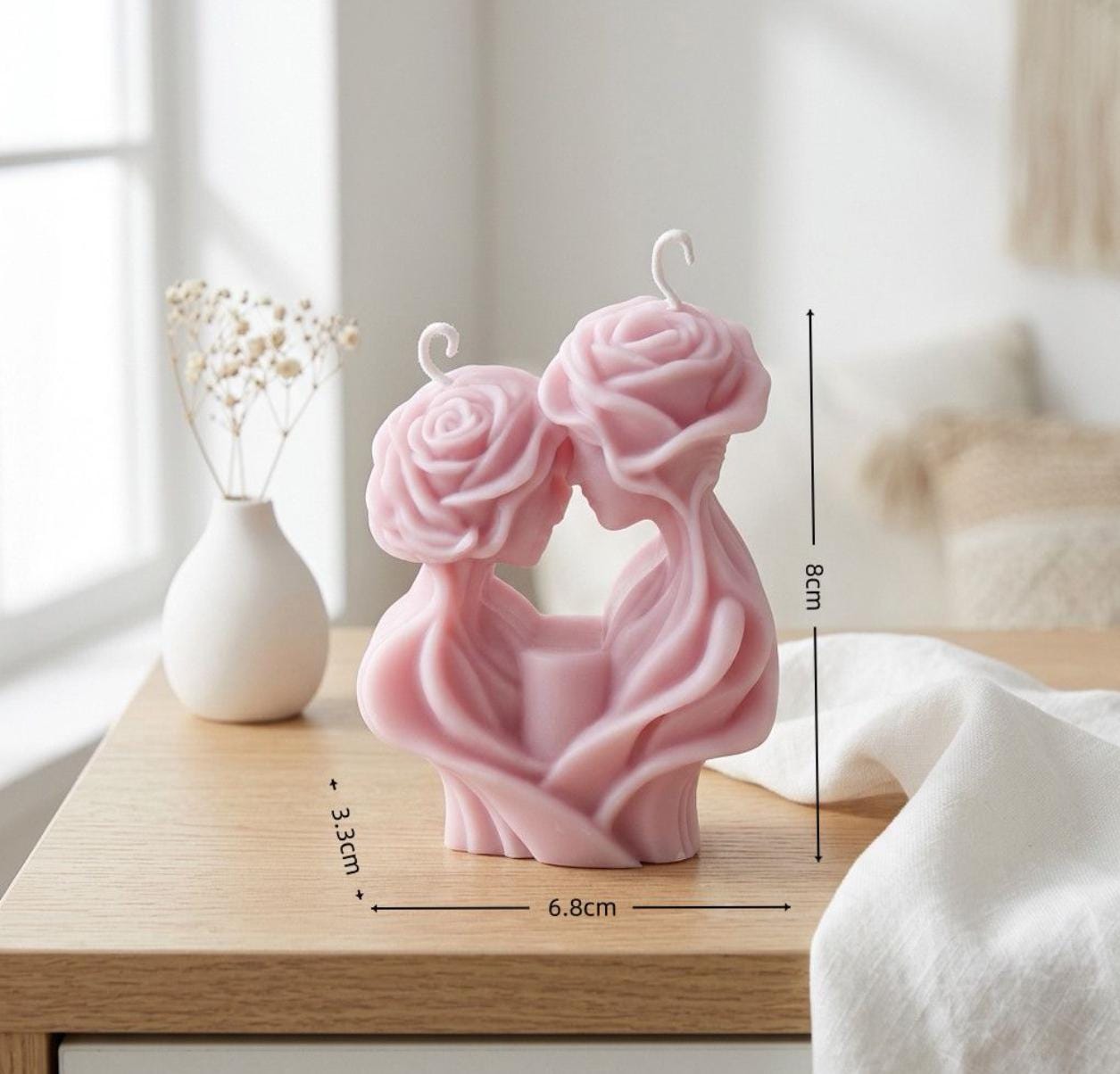 Pink rose-shaped candle with measurements on a wooden surface