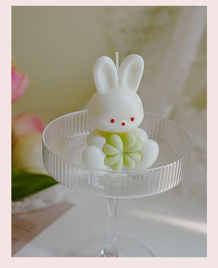 Candle shaped like a bunny on a stand with a floral background