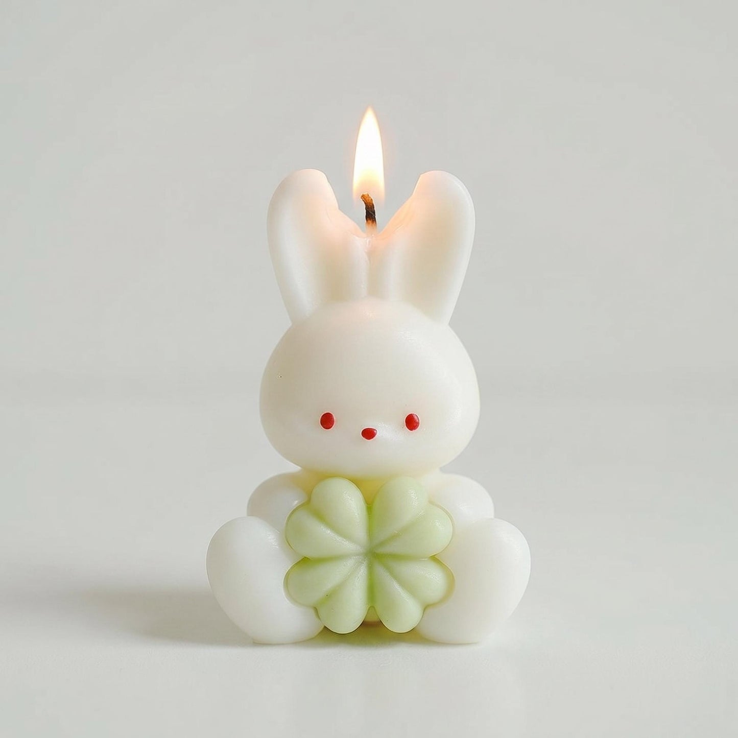 Candle shaped like a cartoon bunny with a flower design on a plain background
