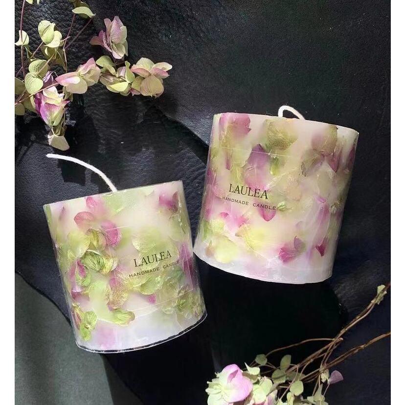 Two floral-patterned candles on a dark surface.