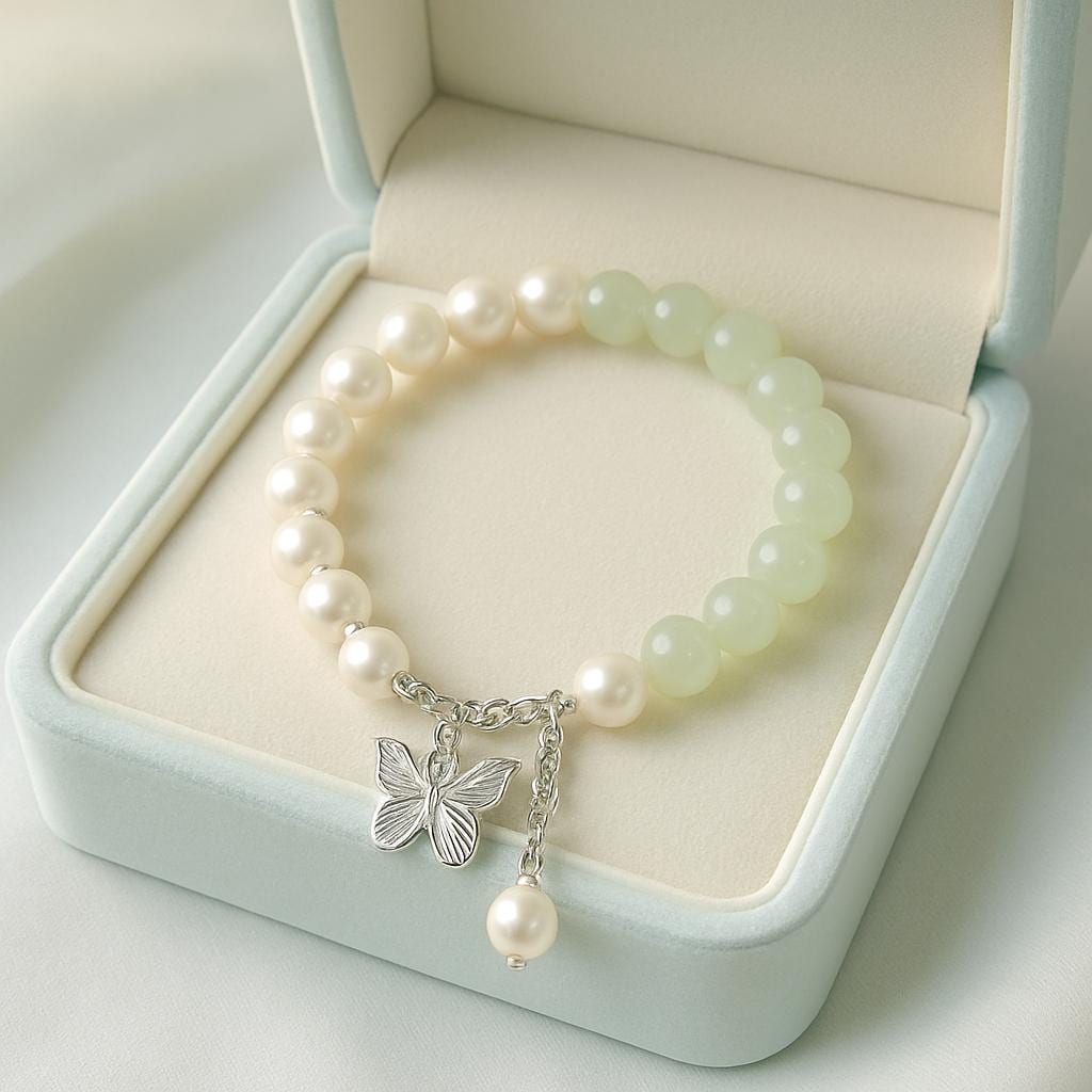 Pearl bracelet with a butterfly charm on a light green jewelry box