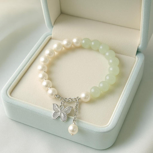 Pearl bracelet with a butterfly charm on a light green jewelry box